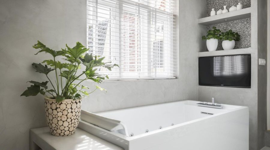 TV in badkamer, vrijstaand bad rechthoekig, witte shutters in badkamer
