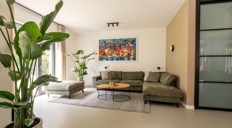 Woonkamer met gietvloer, arts behang en groene bank